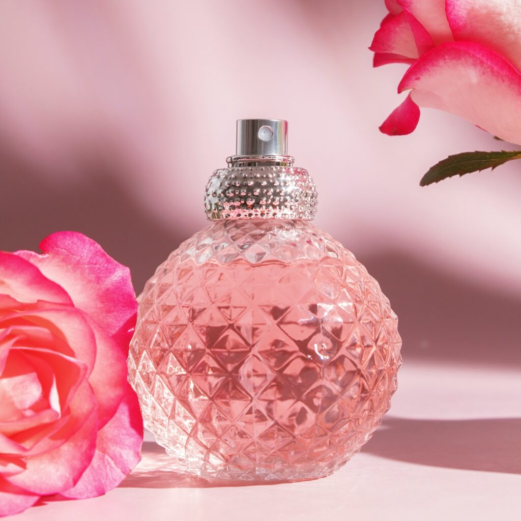 Perfume bottle and rose flowers. Concept of expensive perfume and cosmetics. Floral fragrance for